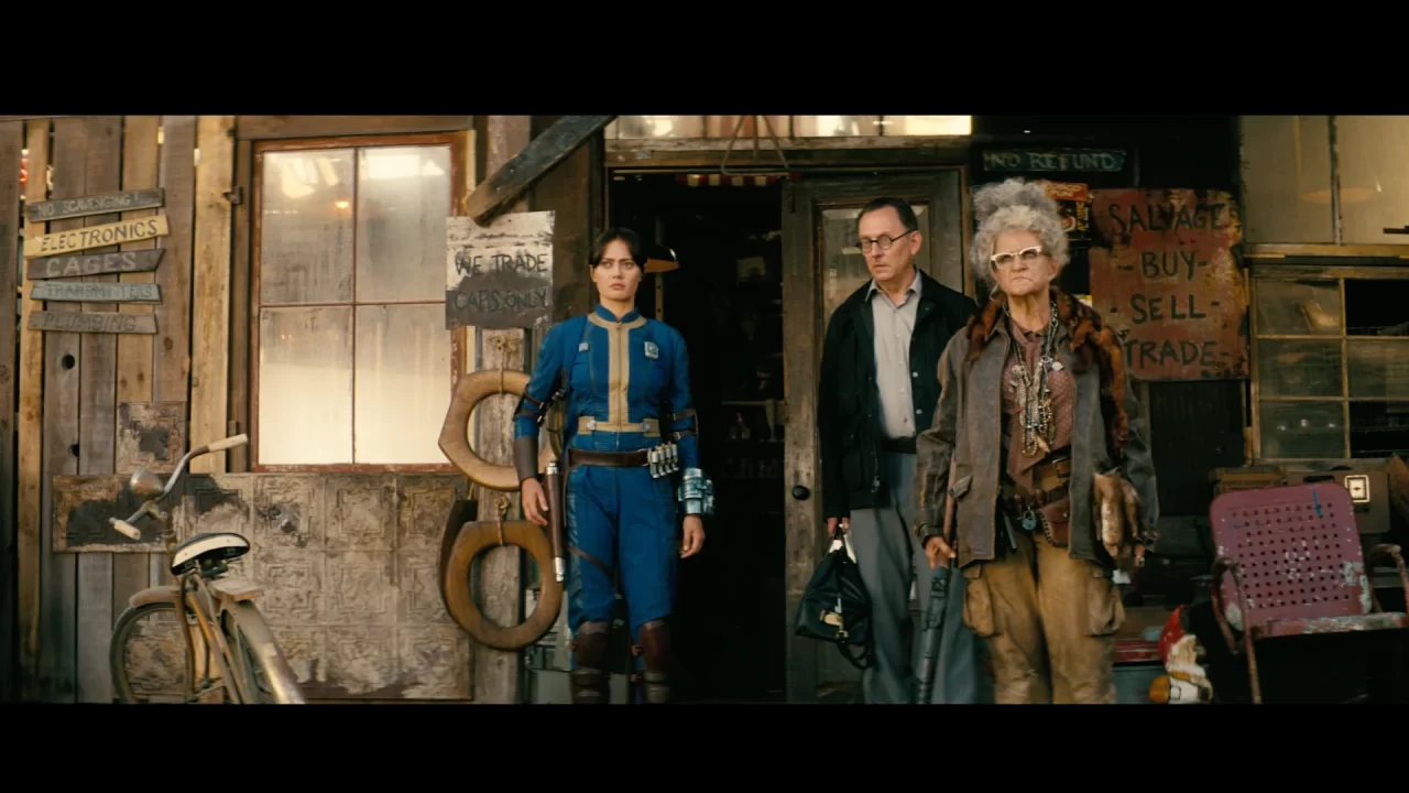 Lucy and two fellow Vault-Dwellers looking concerned in front of a salvage shop.